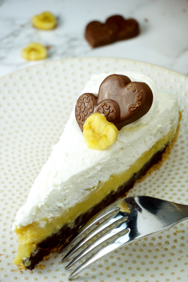 A Slice of black-bottom coconut banana cream pie garnished with a chocolate heart