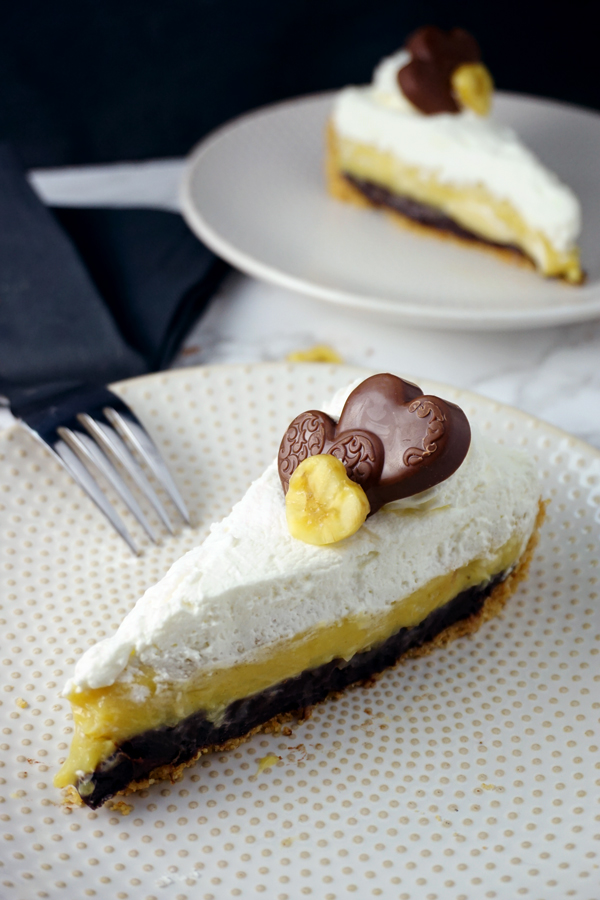 A Slice of black-bottom coconut banana cream pie garnished with a chocolate heart