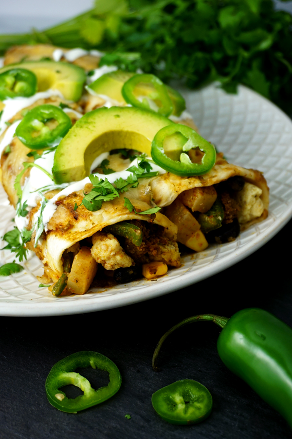 Breakfast enchiladas filled with chorizo and garnished with sour cream, avocado and cilantro