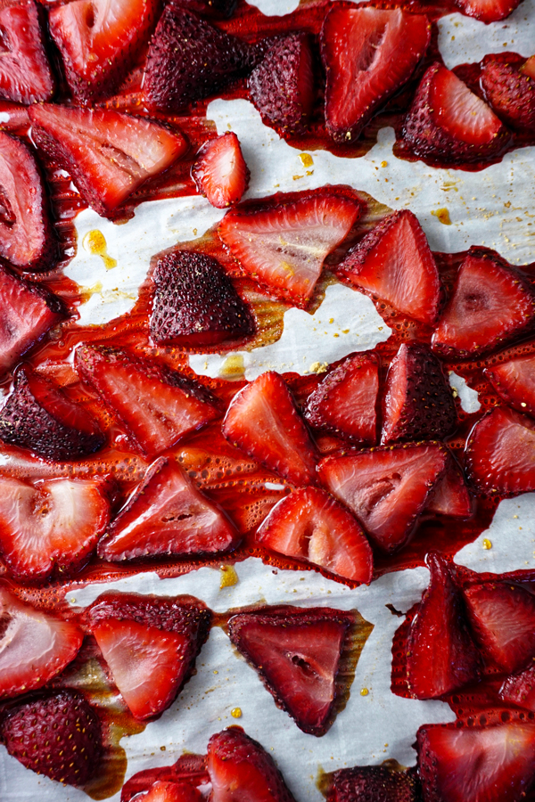 Roasted strawberries sliced on a pan lined with parchment