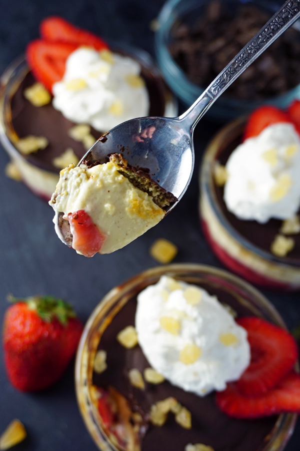 Chocolate covered roasted strawberry pots de creme topped with whipped cream and candied ginger with a spoon