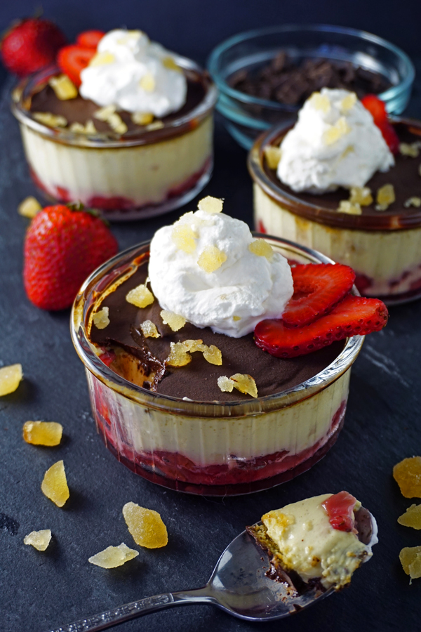 Chocolate covered roasted strawberry pots de creme topped with whipped cream and candied ginger with a spoon