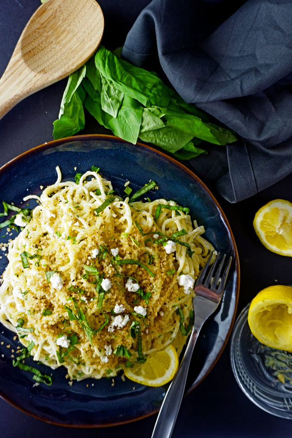 Lemon Goat Cheese Spaghetti with Toasted Pangrattato Breadcrumbs on a blue plate with basil and lemon rinds