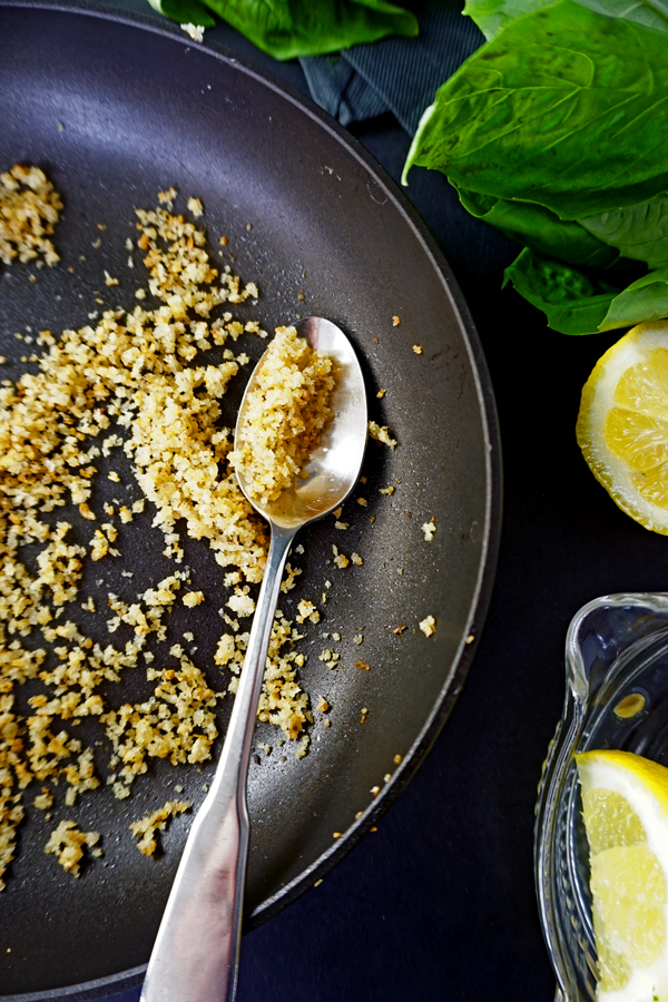 Toasted Pangrattato Breadcrumbs in a skillet with basil and lemon rinds
