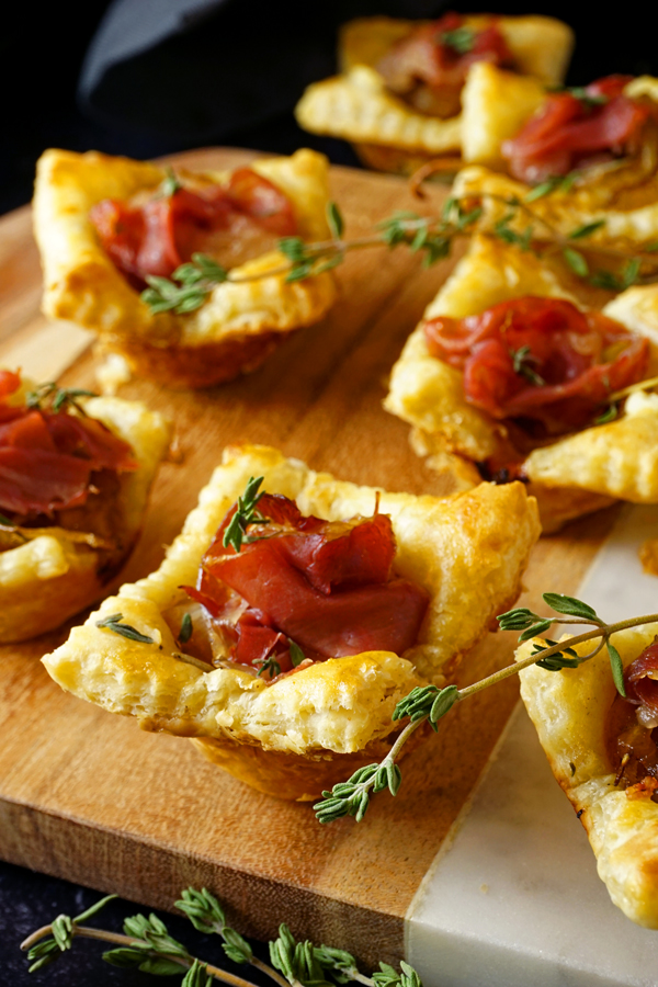 prosciutto-filled caramelized onion tarts on a wood and marble board