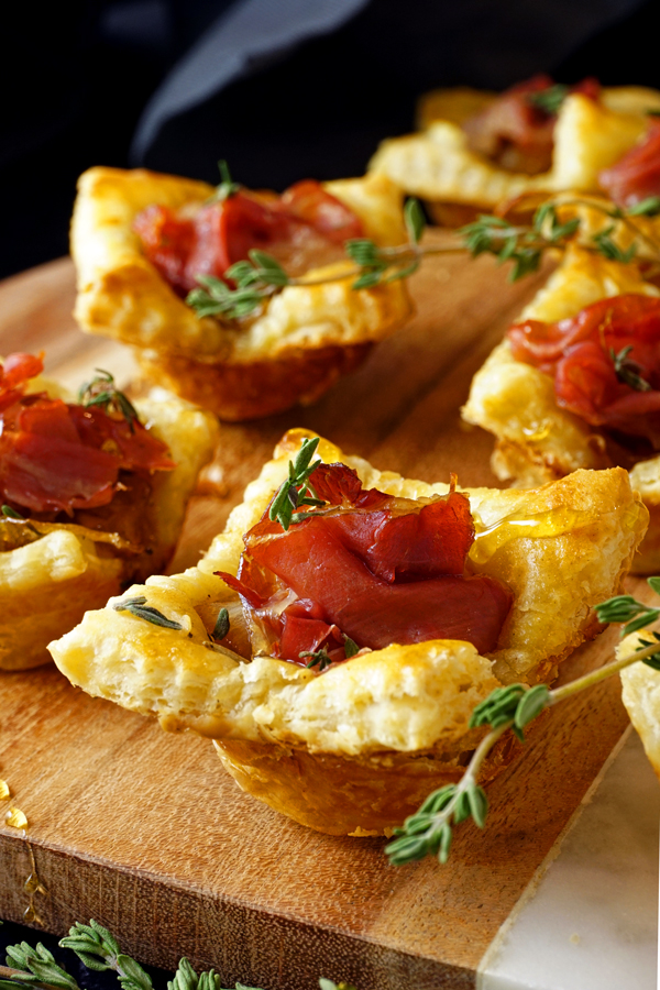 prosciutto-filled caramelized onion tarts on a wood and marble board