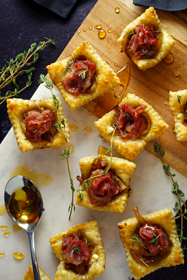 overhead photo of caramelized onion tarts drizzled with honey and filled with prosciutto