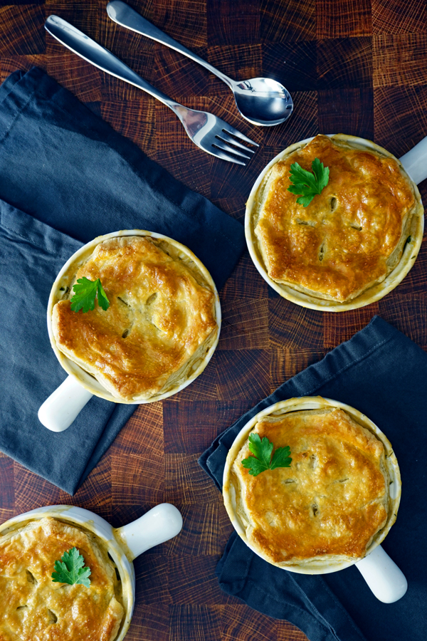 four individual pot pies arranged on butcher block with grey napkins