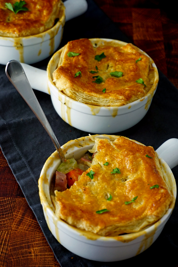 A corned beef and cabbage pot pie with a spoon sticking out of it and parsley