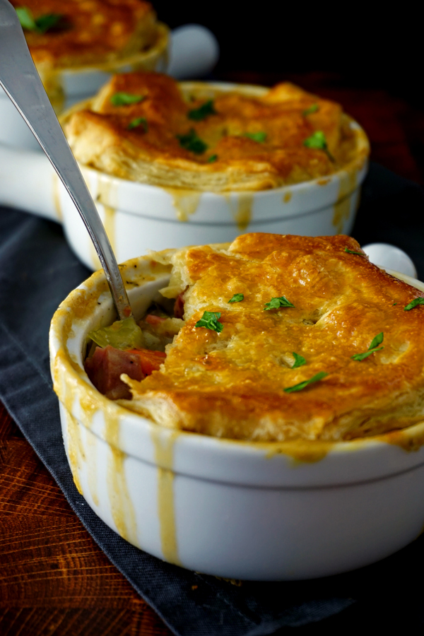 Three corned beef irish pot pies in a row with a bite missing from the one in front