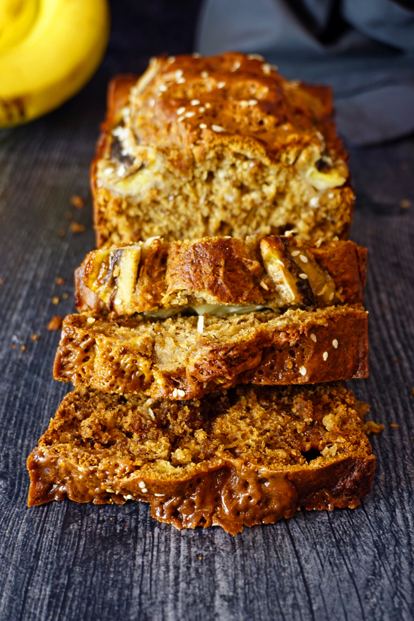 coconut caramel banana bread sliced on an aged wood board