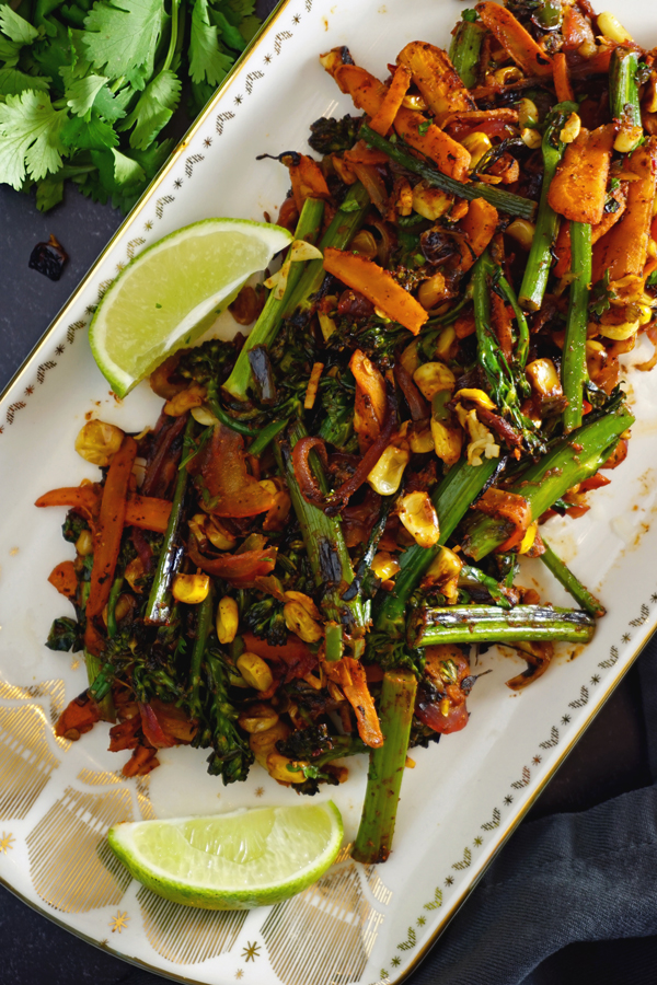 charred vegetables with limes on a white and gold platter for tacos