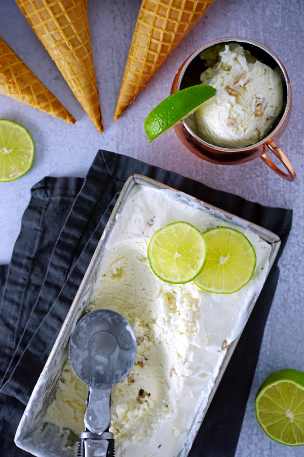 overhead photo of moscow mule ice cream, ice cream cones, lime slices and a copper mug filled with scoops of ice cream