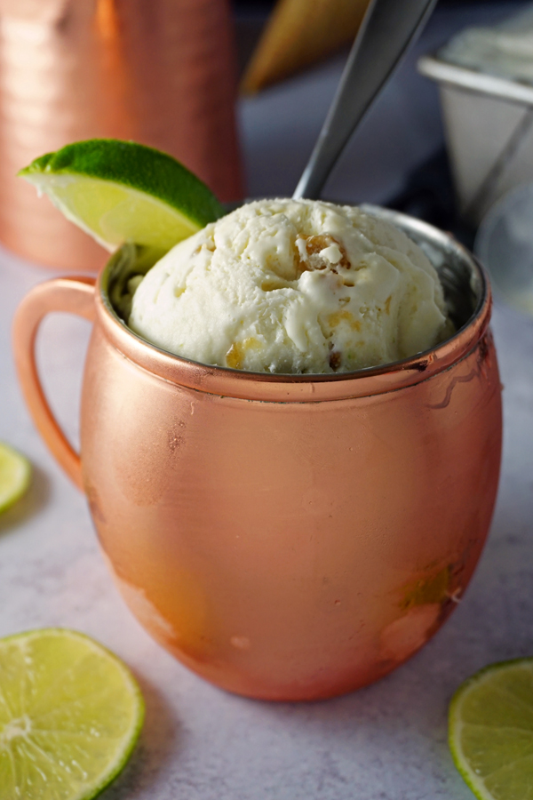 scoops of moscow mule no-churn ice cream in a copper mug, garnished with a lime wedge